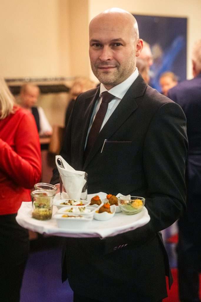 Ein Kellner bei der Tigerpalast-Premiere, der ein Tablett mit Köstlichkeiten in den Händen hält.